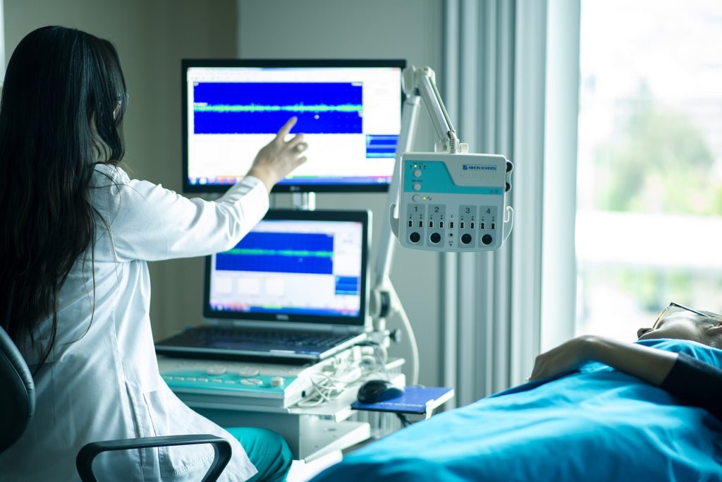 Medical professional analyzing diagnostic data on monitors in a clinical setting